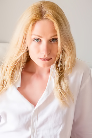 Gorgeous blonde Gerda Rubia is sprawled on her bed in a loose white shirt that leaves her long slender legs bare